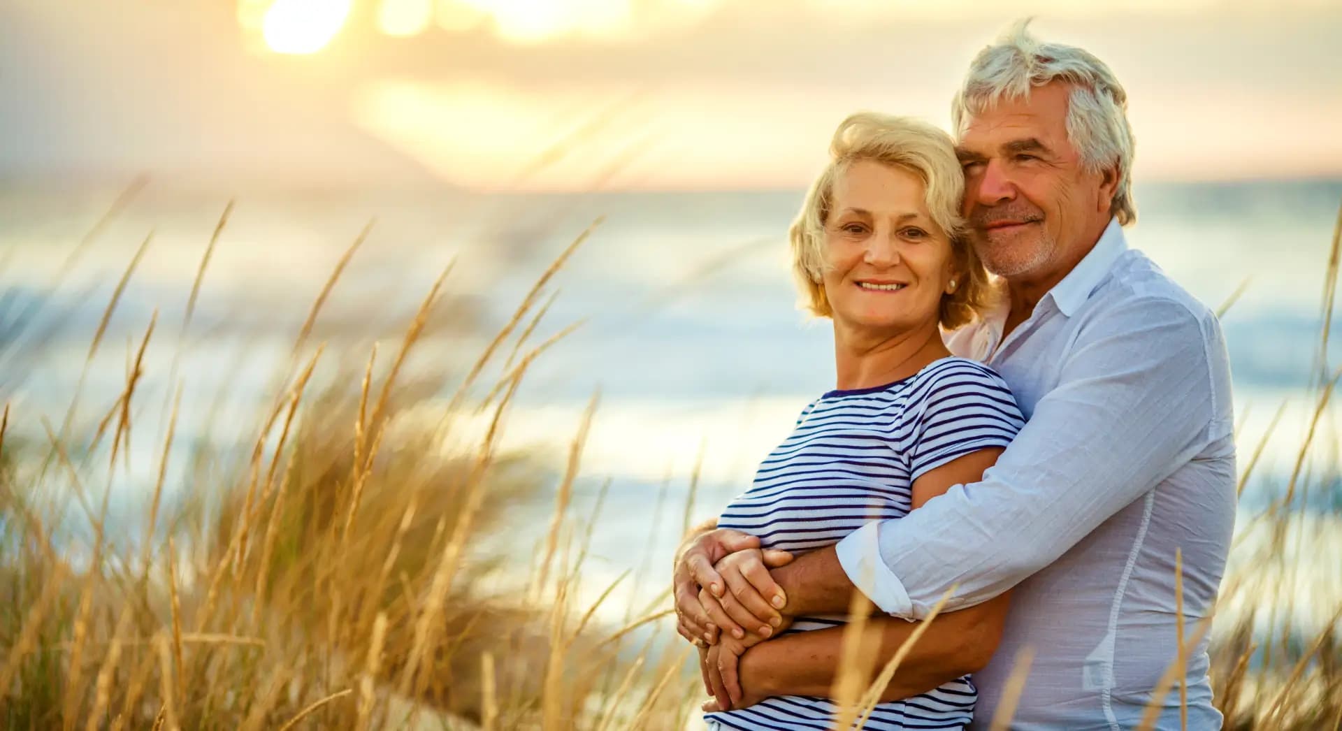 A senior couple embracing at sunset on the beach